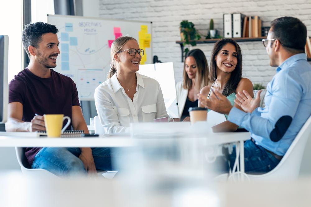 happy coworkers discussing project around table